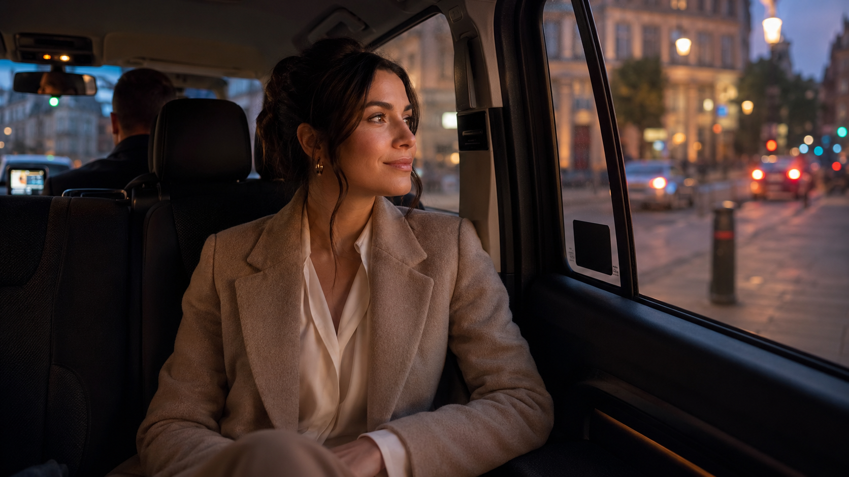 Passenger in the back of a licensed taxi at dusk.